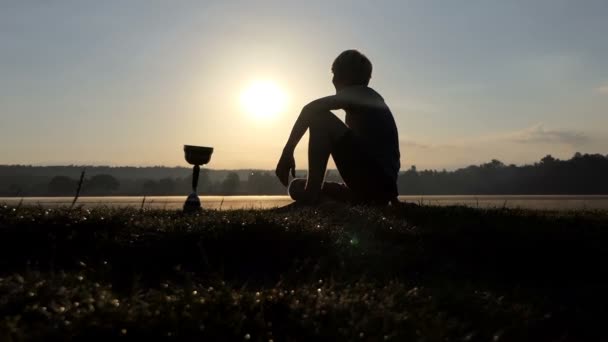 Boldog ember ül a tó partján. A közelben egy győztes tál — Stock videók