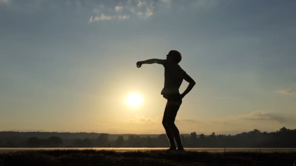 Hombre rubio levanta su cuenco campeón en una orilla del lago al atardecer — Vídeos de Stock