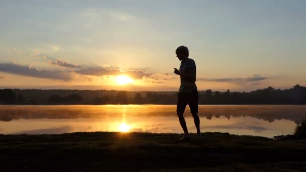 Νεαρός άνδρας κάνει αίθουσα χορού χορός ΠΑΣ σε λίμνη στο ηλιοβασίλεμα — Αρχείο Βίντεο