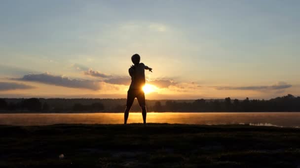 Eleganta mannen danser fri stil på en sjön bank vid solnedgången i slo-mo — Stockvideo
