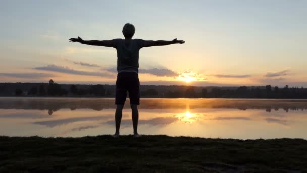 El hombre optimista mantiene las manos a un lado y mira el atardecer en slo-mo — Vídeo de stock