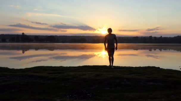 Un jeune homme court d'un lac à un caméraman au coucher du soleil à Pékin — Video