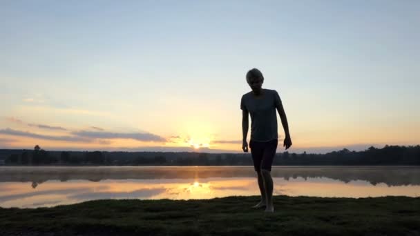 Blond człowiek biegnie od jeziora kamerzystę o zachodzie słońca w slo-mo — Wideo stockowe