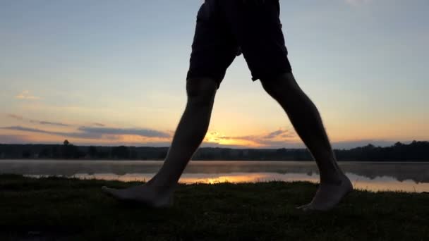 Jovem homem pernas ir ao longo de um lago em um pôr do sol lindo em slo-mo — Vídeo de Stock