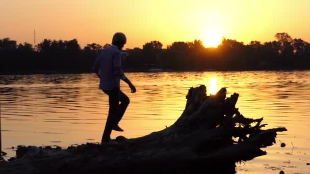 Blond man climbs the tree roots on a lake bank in slo-mo — Stock Video