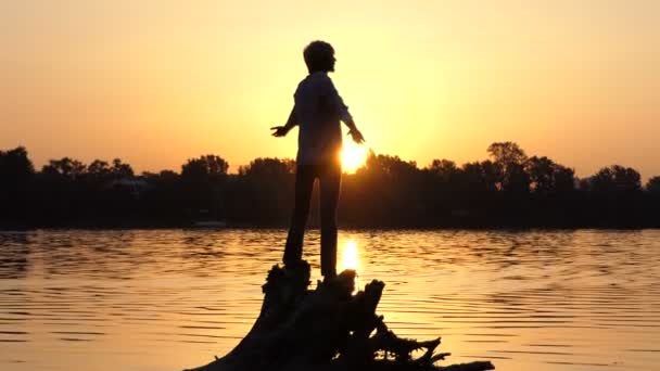 Valiente hombre se para en las raíces de los árboles en una orilla del lago en slo-mo — Vídeo de stock