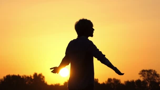 Young man does yoga exercises on a lake bank at sunset in slo-mo — Stock Video