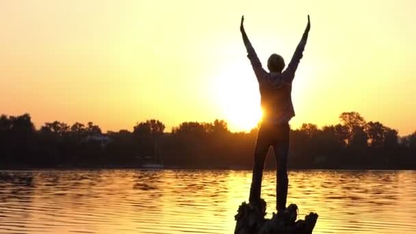 Hombre emocional mantiene un gesto de amor en una orilla del lago al atardecer — Vídeos de Stock
