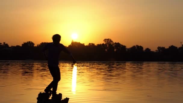 幸せな男は、親指をスローモーションの夕日湖の銀行を発生させます — ストック動画