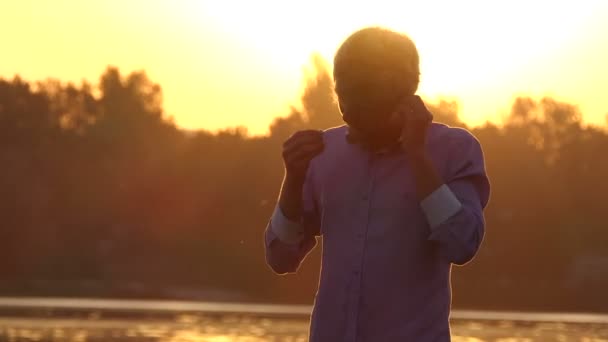 Fiatal ember hallgatja a mobil, a tónál, napnyugtakor a slo-mo — Stock videók