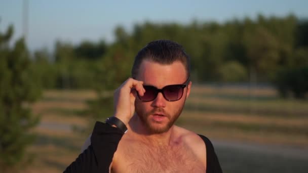 Молодой сексуальный парень надевает солнечные очки в замедленной съемке — стоковое видео