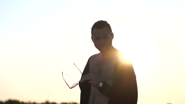 Sexy kerel met een naakt torso sierlijk neemt zijn zonnebril in slow motion — Stockvideo