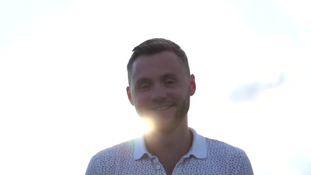 Young brunette guy smiles cute outdoors during sun flare in slow motion — Stock Video