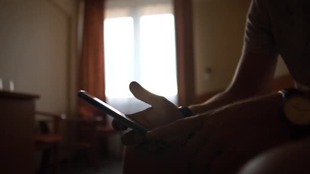 Manliga händer håller en telefon närbild på bakgrunden av ett fönster i ett hotellrum. — Stockvideo