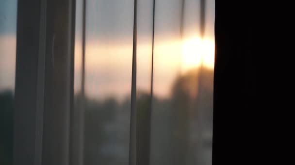 Zonsondergang buiten het raam waarop witte gordijnen — Stockvideo