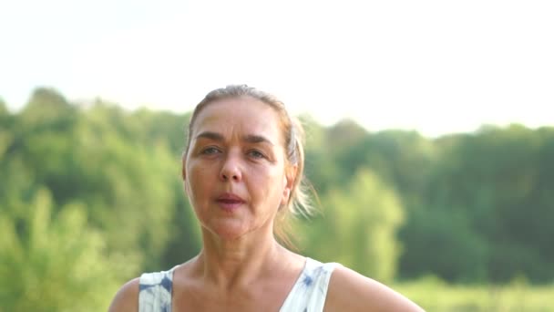 Portret van een vrouw van middelbare leeftijd die glimlacht en in slow motion een luchtkus stuurt. — Stockvideo