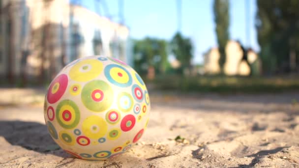 Een kinderbal ligt op de voorgrond op de speelplaats, kinderen spelen op de achtergrond. — Stockvideo