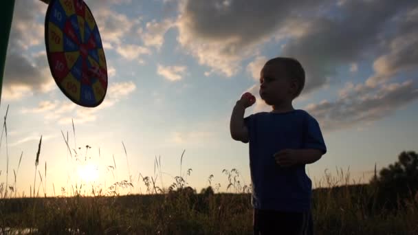 Linda silueta de niño alegre que lanza bolas de velcro en el objetivo en cámara lenta — Vídeo de stock