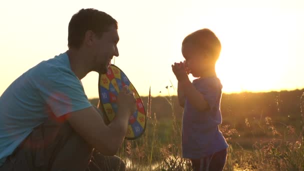 Ojciec i słońce grają w rzutki o zachodzie słońca w zwolnionym tempie. — Wideo stockowe