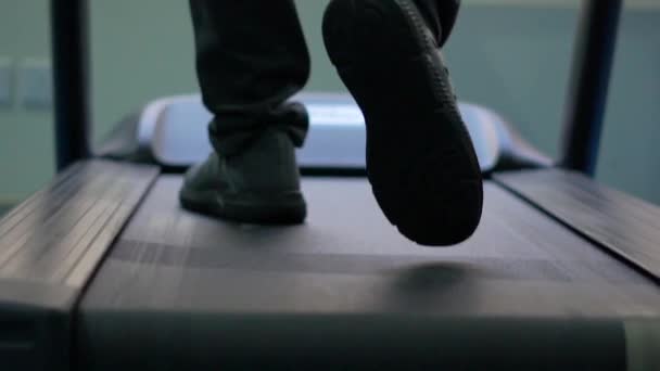 Férfi láb mozog egy futópadon egy tornateremben lassított felvételen — Stock videók