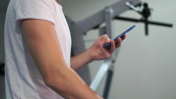 Smart man walking on a treadmill and looking at phone screen in slow motion — Stockvideo