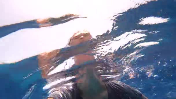 Fröhliche Frau im T-Shirt, die im Slo-mo im Roten Meer schwimmt und nach unten schaut — Stockvideo
