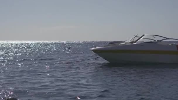 Вечером моторная лодка стоит на якоре у морского берега — стоковое видео