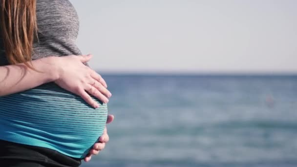 Fiatal nő veregeti terhes gyomrát a Vörös-tenger partján. — Stock videók