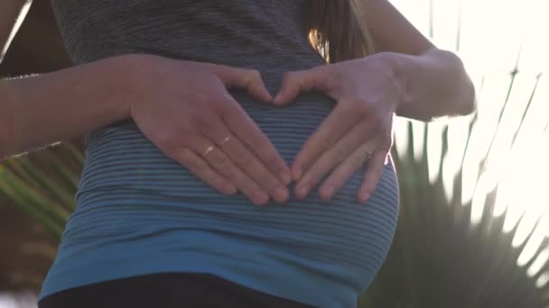 Счастливая женщина держит свой жест любви на своем беременном животе — стоковое видео