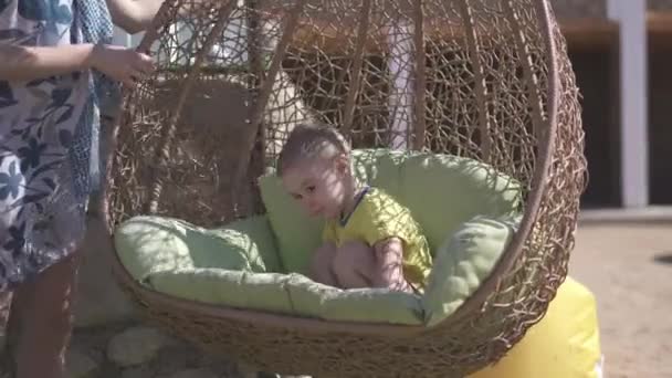 Sonriente niño balanceándose en un columpio de bastón por su madre en slo-mo — Vídeo de stock