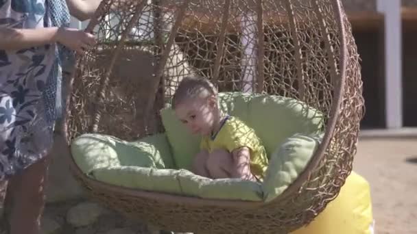 Sonriente niño balanceándose en un columpio de bastón por su madre en slo-mo — Vídeos de Stock