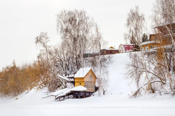 Een landelijk verblijf gebouwd op de oevers van de rivier in de winter. — Stockfoto