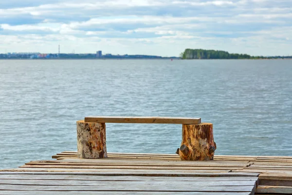 A small makeshift wooden pier and a bench of planks on the shore