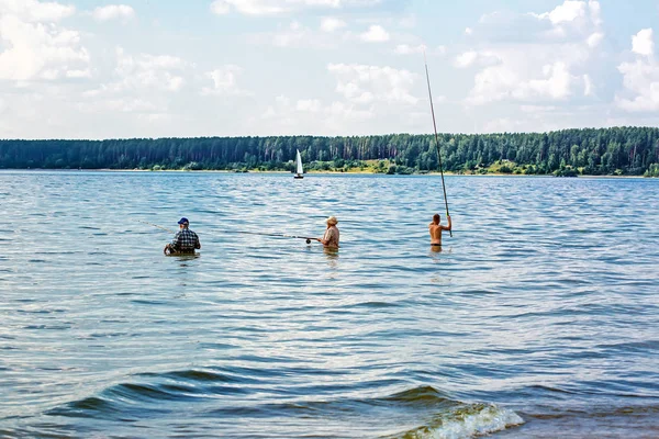 Рыбаки ловят рыбу, стоящую по пояс в воде с поплавком. — стоковое фото