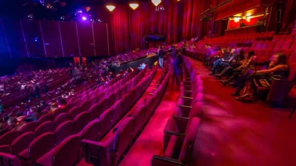 Los espectadores se reúnen en el auditorio y ven el espectáculo en el timelapse del teatro. Gran salón con sillones rojos asientos — Vídeos de Stock