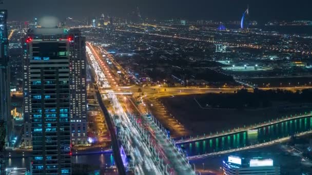 Dubai business bay torn upplyst på natten timelapse. Takterrass med utsikt över några skyskrapor och nya torn under konstruktion. — Stockvideo