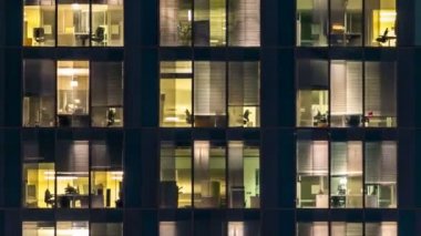 Cam ve çelik ışıklandırmadan oluşan çok katlı binanın penceresi ve zaman ayarlı insanlar