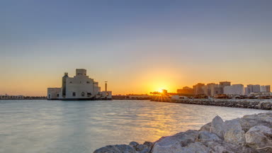 Güneş doğarken geçen balıkçı tekneleriyle Doha Limanı ve arka planda İslami Sanat Müzesi.