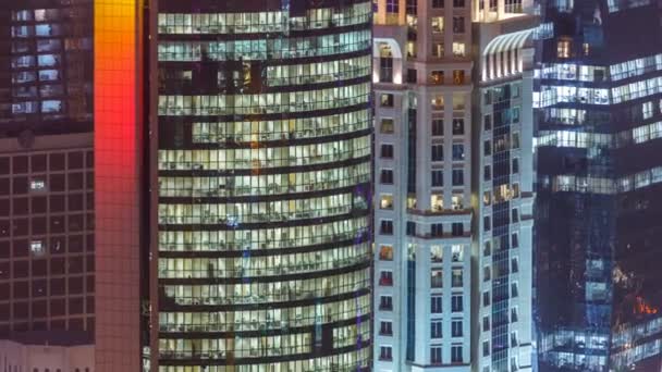 Хронологія вікон багатоповерхової будівлі зі скляного та сталевого офісного освітлення та робочих людей всередині — стокове відео
