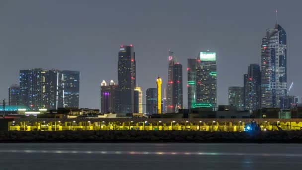 Moderne Skyline Dubais bei Nacht mit beleuchteten Wolkenkratzern über der Wasseroberfläche — Stockvideo