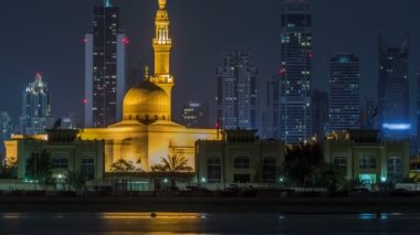 Modern Dubai şehir manzarası timelapse Rashid Al hadis Camii ile su yüzeyi üzerinde ışıklandırılmış gökdelenler ile gece