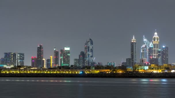 Moderní timelapse panorama města Dubaj v noci s osvětlenými mrakodrapy nad vodní hladinou — Stock video