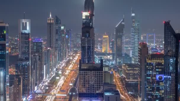 Escénica línea del horizonte del centro de Dubai por la noche timelapse. Vista de la azotea de la carretera Sheikh Zayed con numerosas torres iluminadas . — Vídeos de Stock