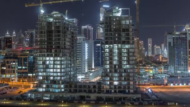 Flygfoto över en skyskrapa under uppbyggnad med enorma kranar natt timelapse i Dubai. — Stockvideo