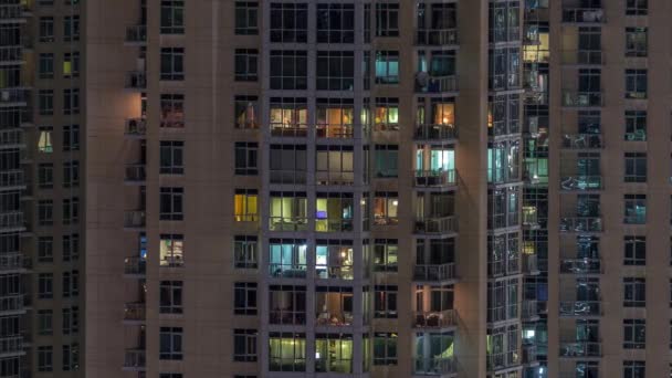 Okna wielokondygnacyjnego budynku z oświetleniem wewnątrz i poruszających się osób w apartamentach timelapse. — Wideo stockowe