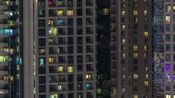 Ramen van het gebouw met meerdere verdiepingen met verlichting binnen en bewegende mensen in appartementen timelapse. — Stockvideo