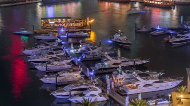 Dubai Marina körfezindeki iskeleye park etmiş lüks yatlar. Şehir hava manzaralı gece manzaralı.