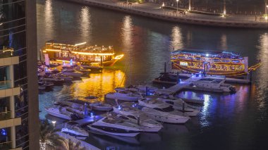 Dubai Marina körfezindeki iskeleye park etmiş lüks yatlar. Şehir hava manzaralı gece manzaralı.