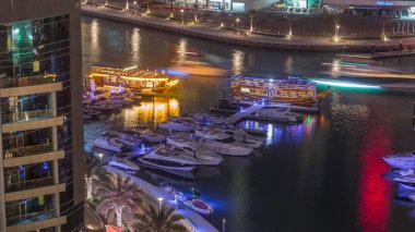 Dubai Marina körfezindeki iskeleye park etmiş lüks yatlar. Şehir hava manzaralı gece manzaralı.