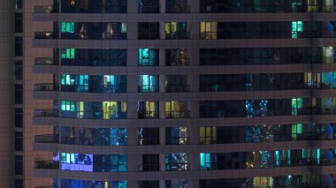 Geceleri apartmanda insanların oturduğu parlak pencereler..